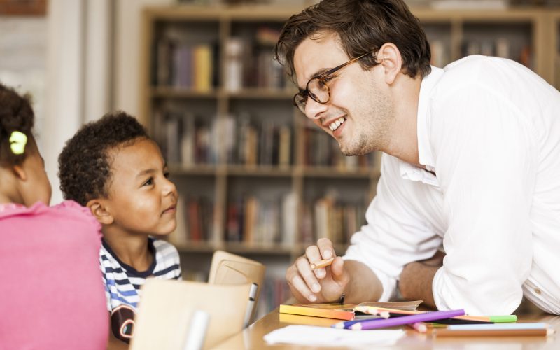 Happy male teacher teaching students during art class