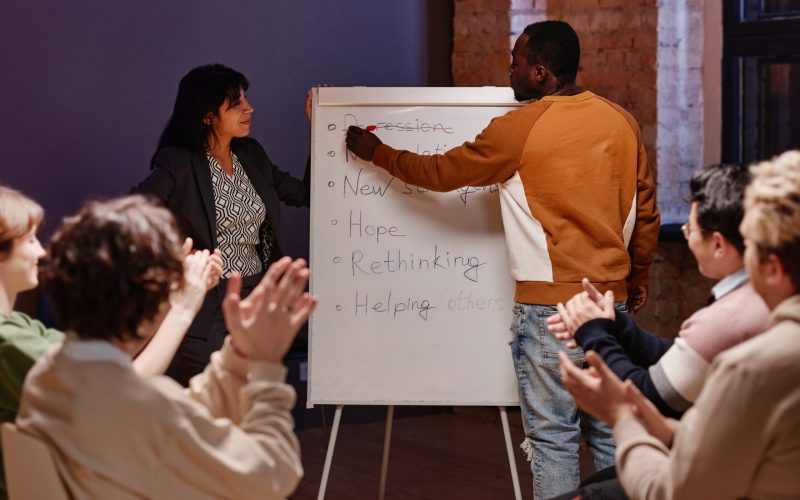 Horizontal shot of professional psychologist and group of clients planning next stages for overcoming and treating depression